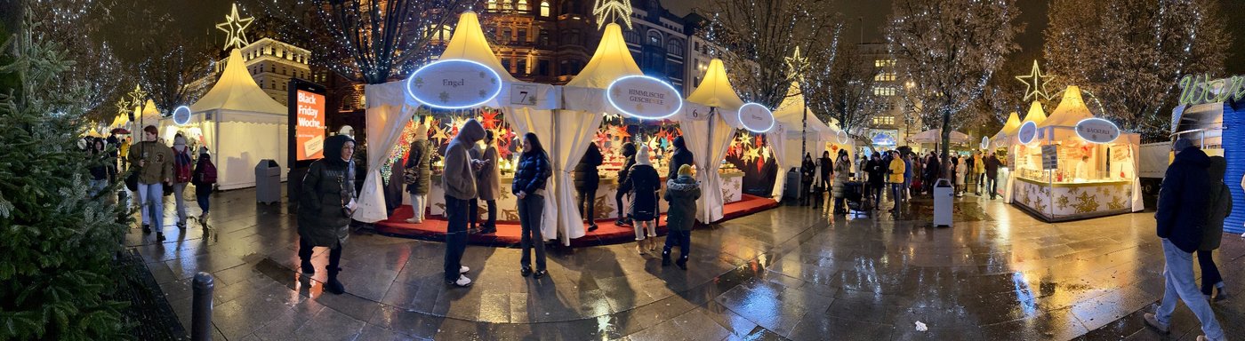 Abendliche Weihnachtsmarktgasse mit beleuchteten Ständen Engel und Himmlische Geschenke