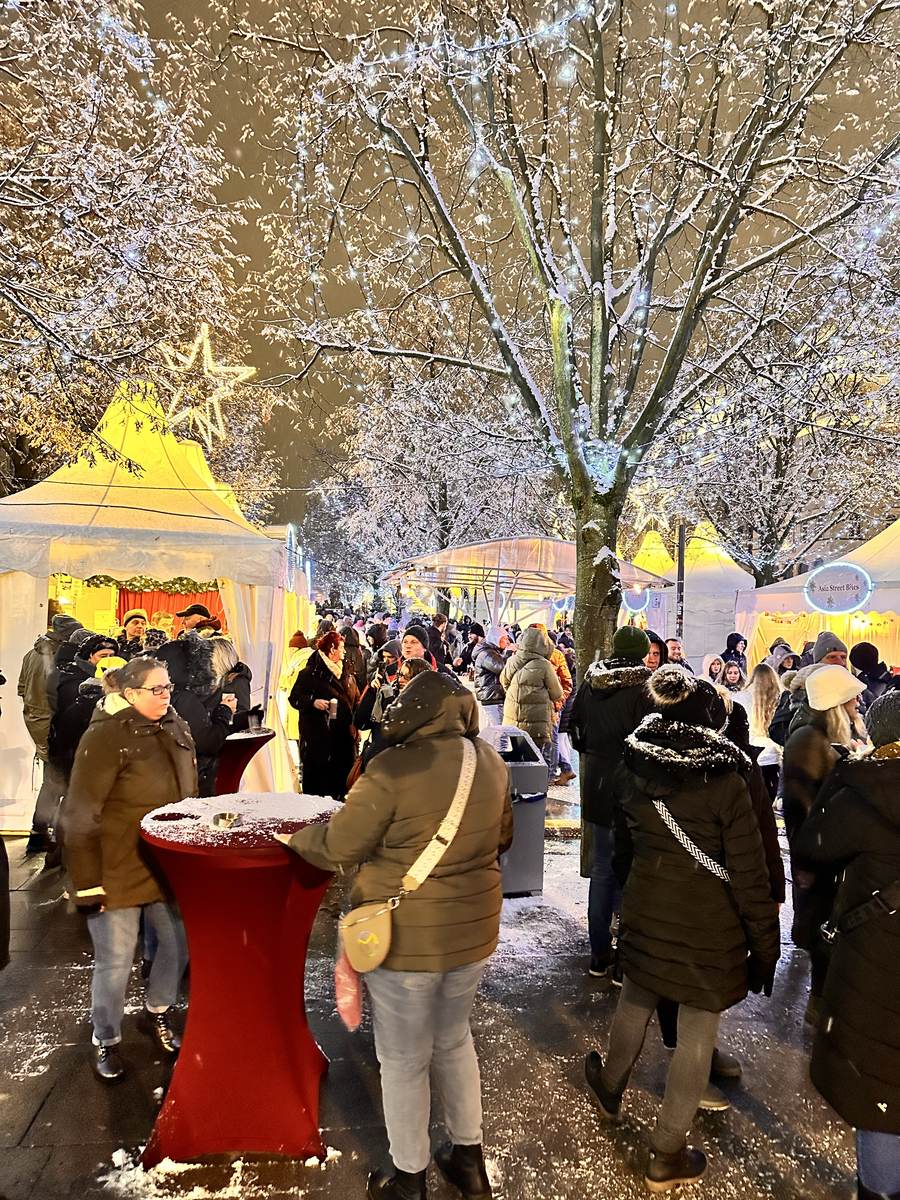 Besucher im Schnee zwischen den Lichterbäumen